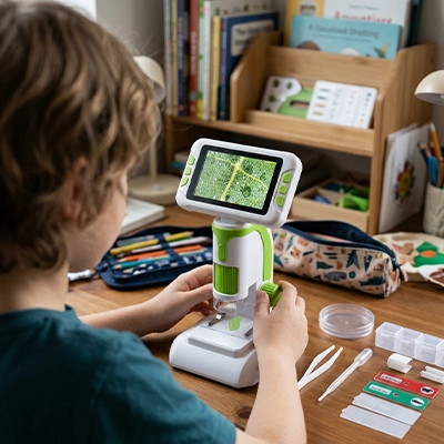 un enfant devant son Microscope enfant développe ses capacité à se concentrer pour de plus longue période au travers du jeu scientifique.
