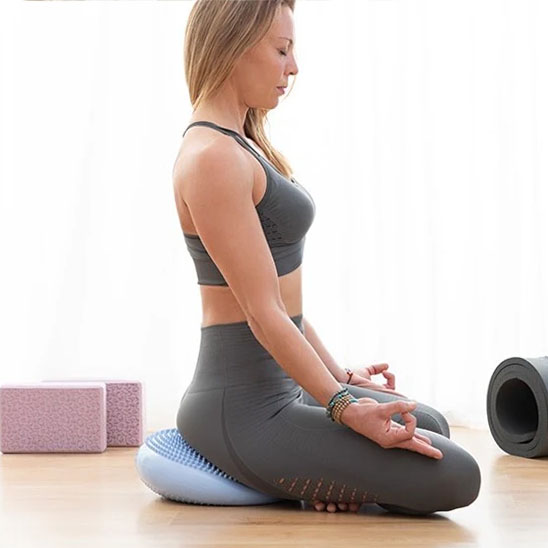 Une Femme assise méditant sur tapis Pilates, posture zen, concentrée.