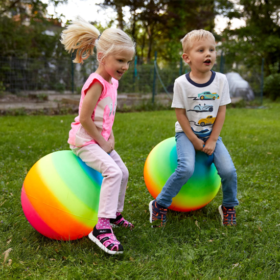 2 enfants heureux avec leur Ballon sauteur arc-en-ciel fluo un exercice complet et amusant