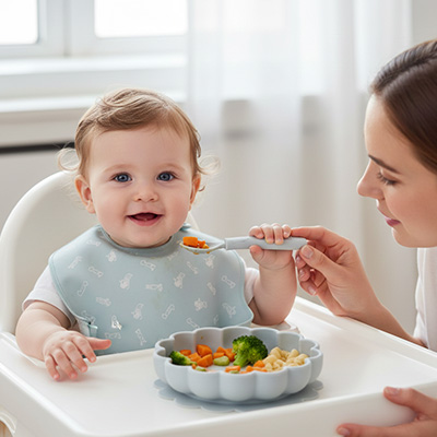 une maman tend la cuillère à son enfant avec Assiette bébé ventouse fleur coloris bleu