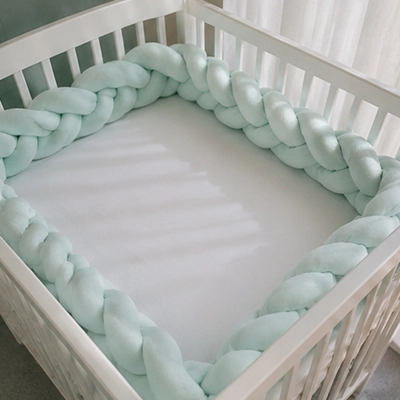 Tresse de lit Cocooning verte utilisée comme décoration dans la chambre de bébé
