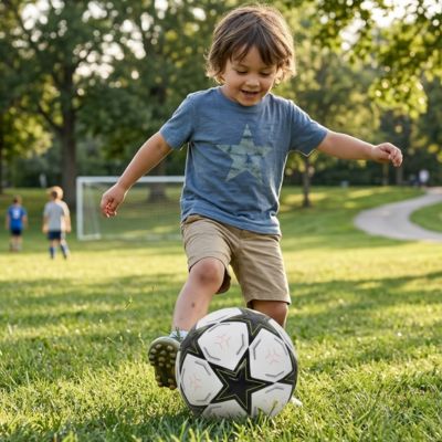 un gamin profite du temps ensoleillé pour jouer avec son Ballon foot étoile